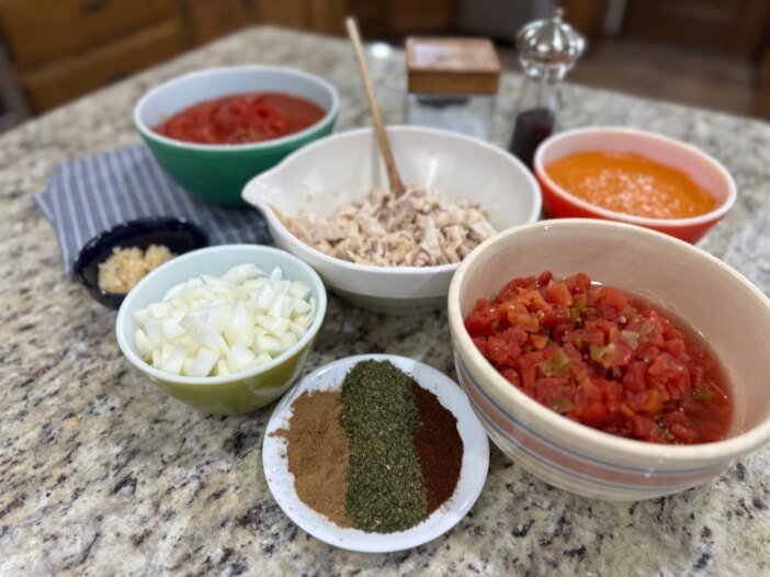 Ingredients for easy chicken tortilla soup including shredded chicken, diced tomatoes, onions, and spices